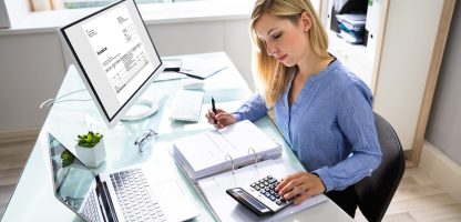 Young Businesswoman Calculating Bill With Computer And Laptop On Desk